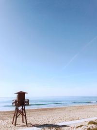 Lifeguard hut on beach against clear blue sky