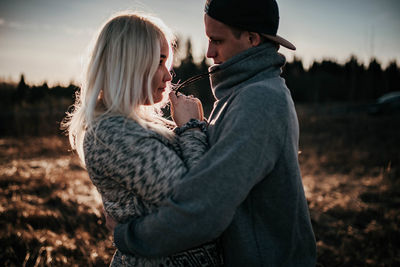 Side view of couple embracing while standing on land