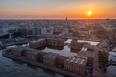 High angle view of river by buildings against sky during sunset