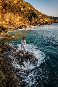 Full length of man standing on rock in sea