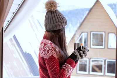 Rear view of woman drinking coffee during winter