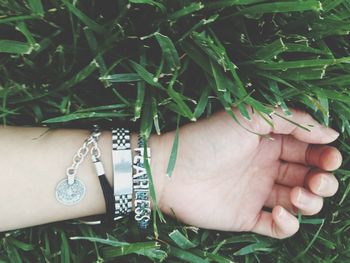 Cropped hand on woman wearing bracelet on plants