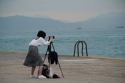 Rear view of woman photographing sea shore