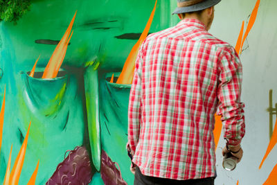 Rear view of man making graffiti on wall