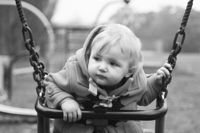 Portrait of cute baby sitting on swing at playground