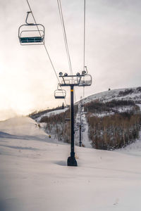 Ski lift over snow covered field against sky