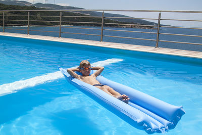 High angle view of shirtless boy relaxing in swimming pool