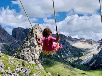 Rear view of person on rock against sky