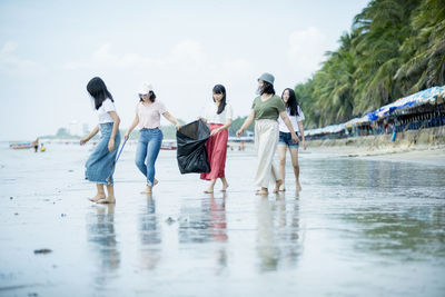 Female friends collecting garbage at beach
