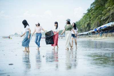 Rear view of people walking on wet road during rainy season