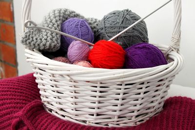 Close-up of multi colored wool balls in basket on table at home