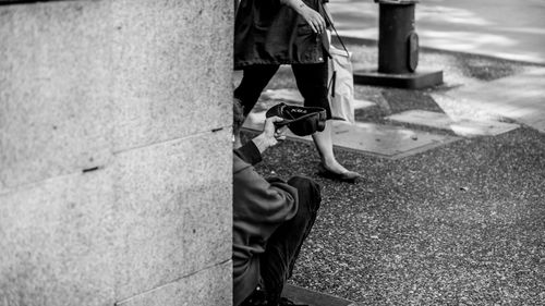 Beggar begging while sitting at sidewalk