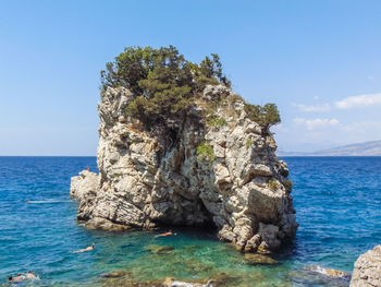 Rock formation in sea against blue sky