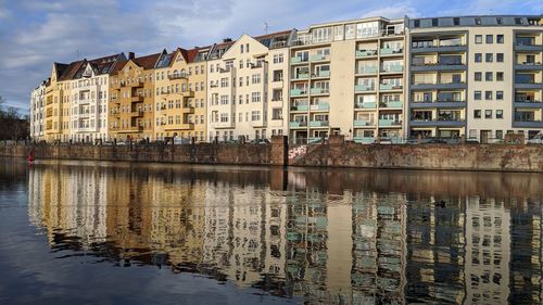 Reflection of buildings on river against sky