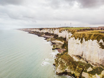 Scenic view of beach against cloudy sky. scenic view of cliff. scenic view of wind turbine. 