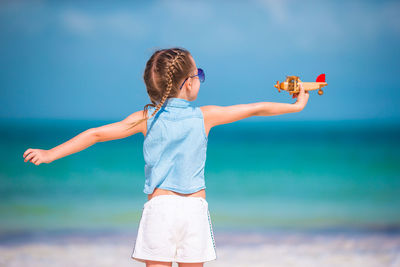 Low angle view of girl with arms raised against sky