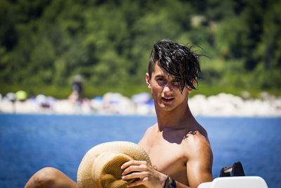 Portrait of shirtless man riding boat on lake