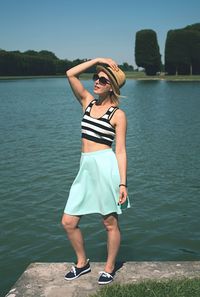 Full length of young woman standing by lake