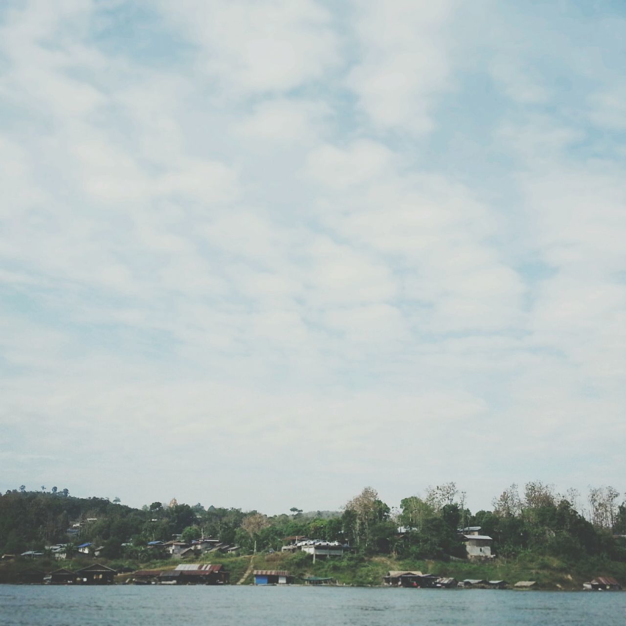 water, sky, waterfront, cloud - sky, tree, river, tranquility, tranquil scene, lake, cloudy, scenics, nature, beauty in nature, cloud, sea, day, outdoors, idyllic, built structure, no people