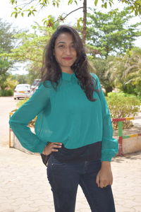 Portrait of smiling young woman standing against trees