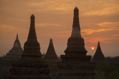 Stupas against dramatic sky during sunset