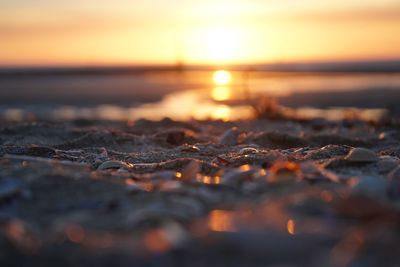 Surface level of pebble beach against sunset sky