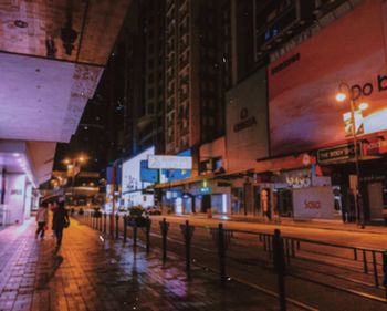 Wet street amidst buildings in city at night