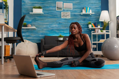 Young woman using phone while sitting on table