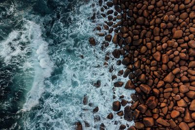 High angle view of waves splashing on rocks at beach