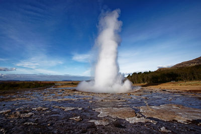 Smoke emitting from volcanic landscape against sky