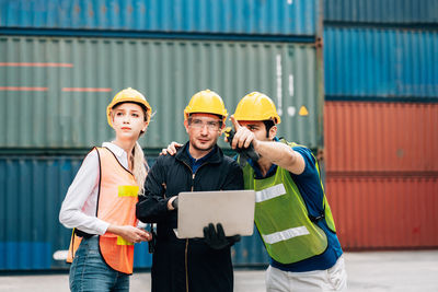 Engineers looking away while sanding against cargo containers