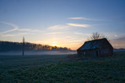 House on field against sky during sunset