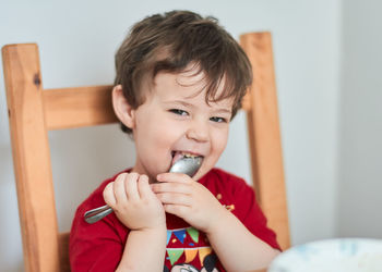 A boy is having fun at the breakfast table eating oatmeal