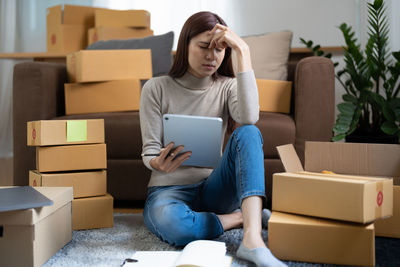 Young woman using laptop while sitting on sofa at home