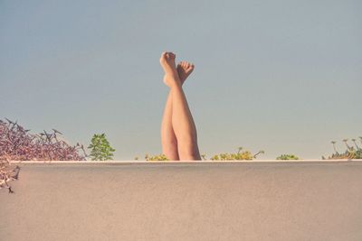 Midsection of woman with arms raised against clear sky