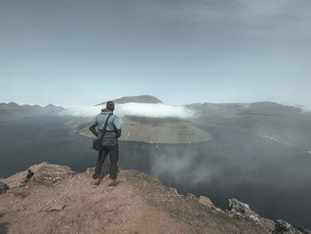 Rear view of man standing on mountain against sky