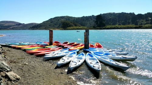 Colorful red and blue kayaks moored in river against mountains and sky