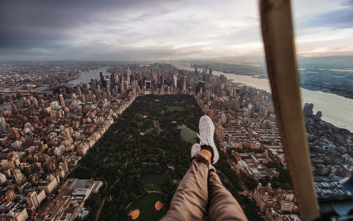 Low section of man sitting in helicopter over buildings in city