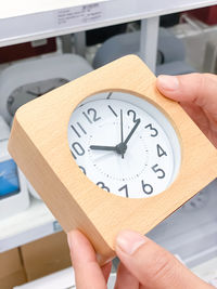 Midsection of person holding clock at home