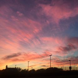 Silhouette of electricity pylons against dramatic sky