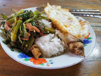 Morning glory with pork curry and fried egg on top of stream rice, thai street food
