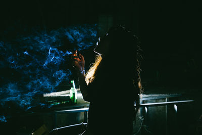 Rear view of woman standing by illuminated lamp