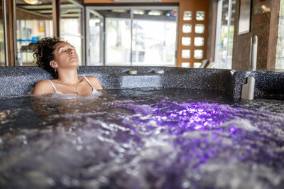 Mixed race woman relaxing in a hot tub during a spa day.