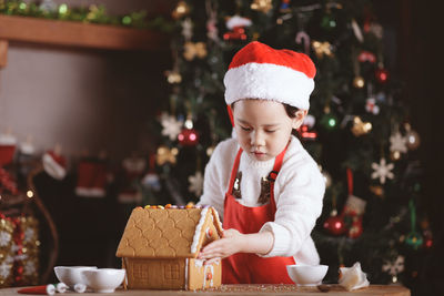 Young girl making gingerbread house at home