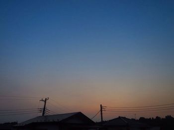 Silhouette electricity pylon against sky during sunset