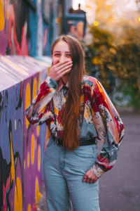 Young woman standing against wall