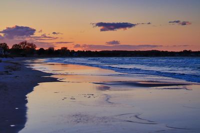 Scenic view of beach against sky at sunset