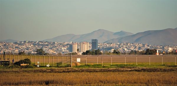 Scenic view of field by buildings against sky