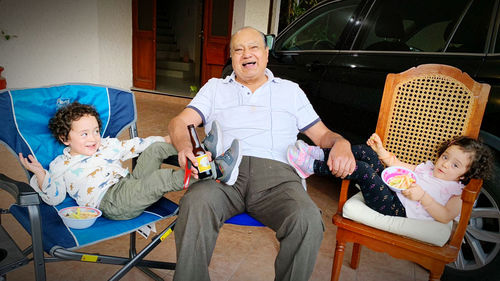 Full length of father and daughter sitting on people