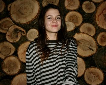 Portrait of smiling man standing on wooden logs